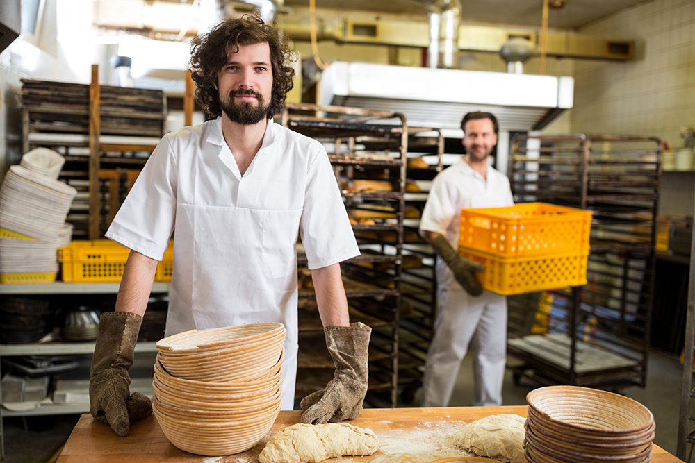 Two smiling bakers working in bakery kitchen